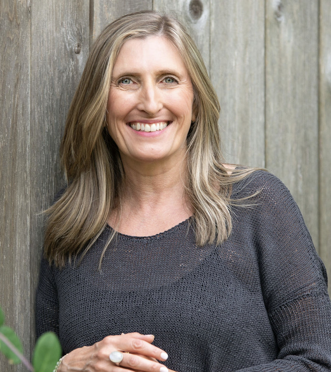 Annika Ek standing in front of a wood fence.